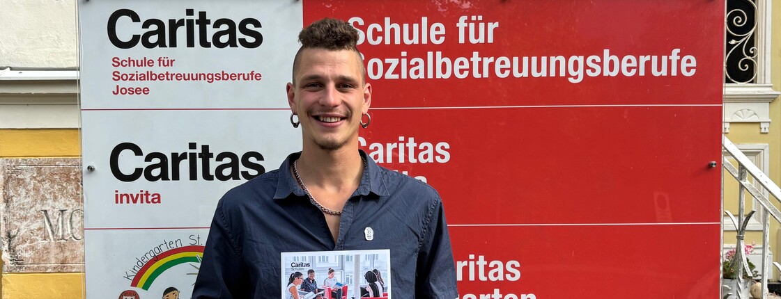 Junger Mann lächelt und hält eine Urkunde in die Kamera